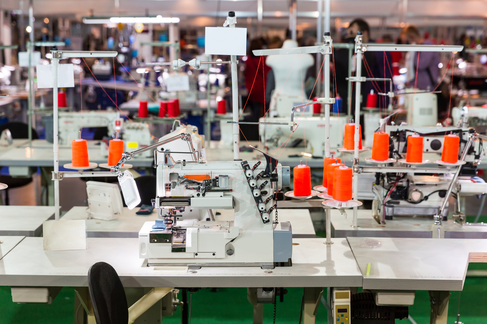 Apparel PLM software supporting production workflows on a garment manufacturing floor with industrial sewing machines