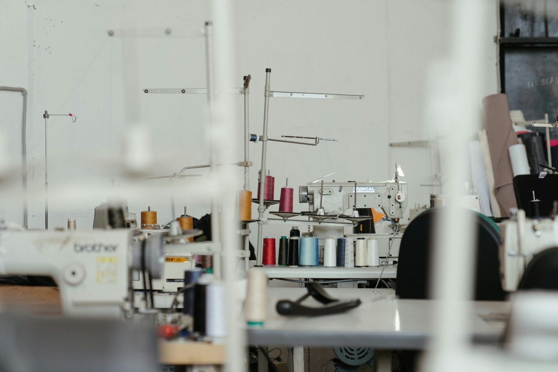 Industrial sewing machines and spools of thread on a garment factory floor illustrating apparel ERP solutions New York manufacturers use for clothing and textile production