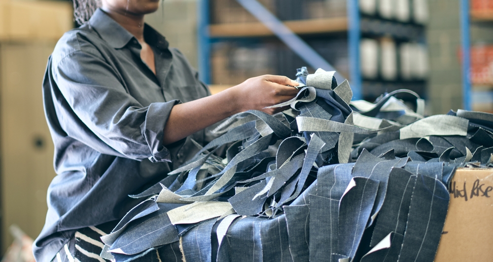 Factory worker sorting cut fabric pieces on a production floor supported by garment manufacturing ERP software that tracks inventory, cut planning, and execution workflows.