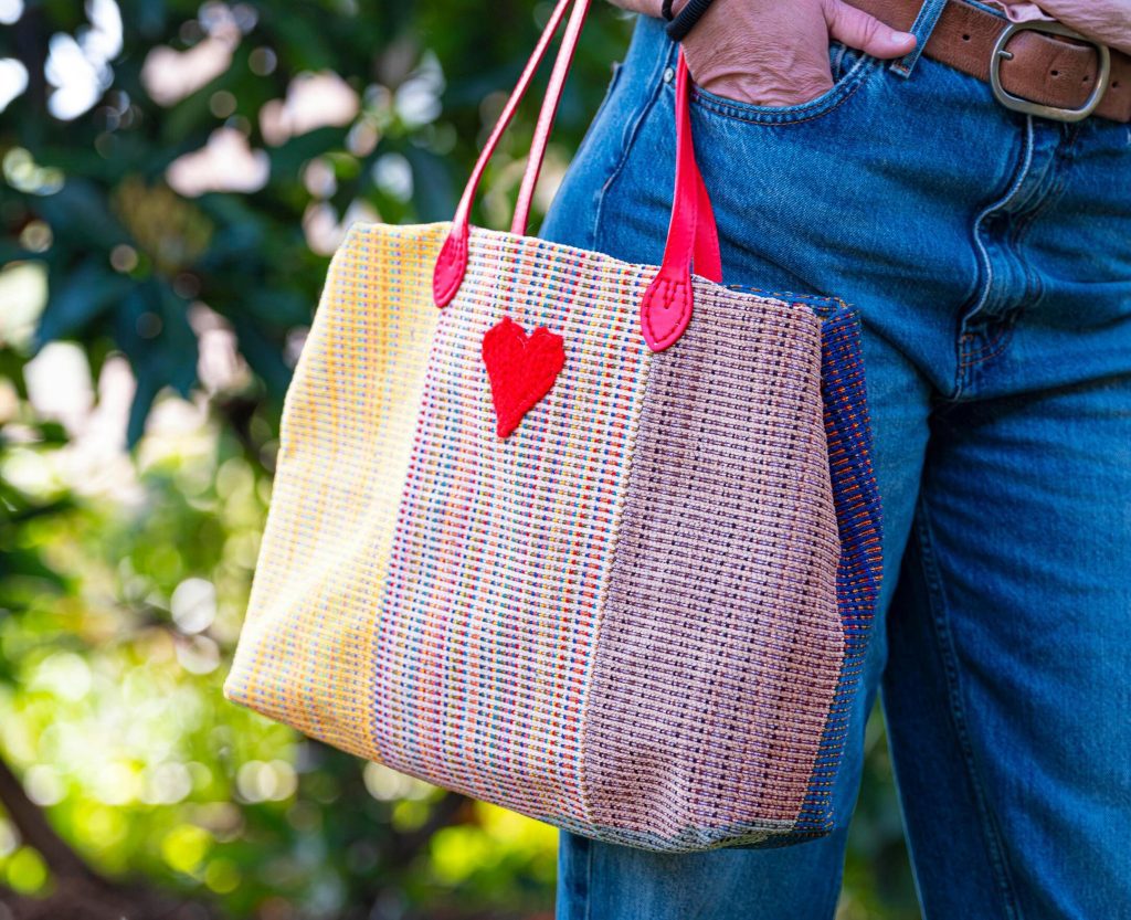 Woven tote bag with mixed fabric panels and hardware details manufactured using PolyPM, an ERP for accessories built by Polygon Software for multi-component production.