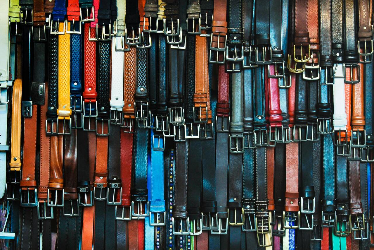 Collection of leather belts with metal buckle hardware in multiple colorways managed through an ERP for accessories to track material variation and component inventory.