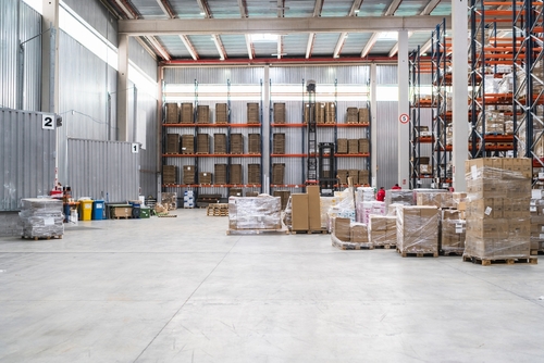 Large warehouse with racking shelves and palletized inventory managed with apparel order management software