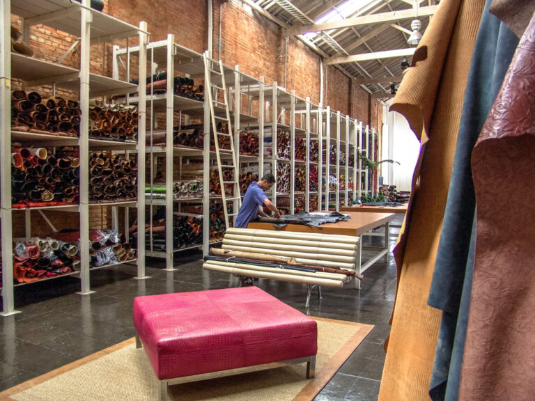 Worker reviewing fabric rolls in a textile material storage facility managed with PolyPM ERP inventory software for textile manufacturing by Polygon Software
