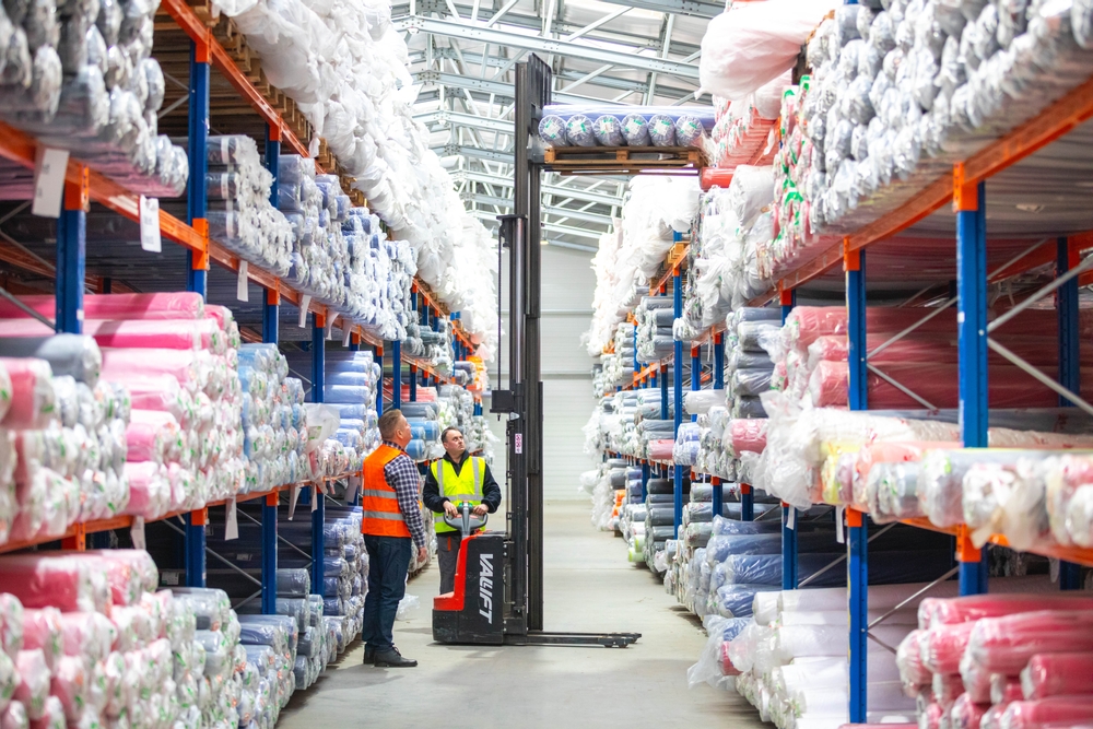 Textile warehouse workers managing fabric roll inventory with forklift using PolyPM ERP inventory software for textile manufacturing by Polygon Software