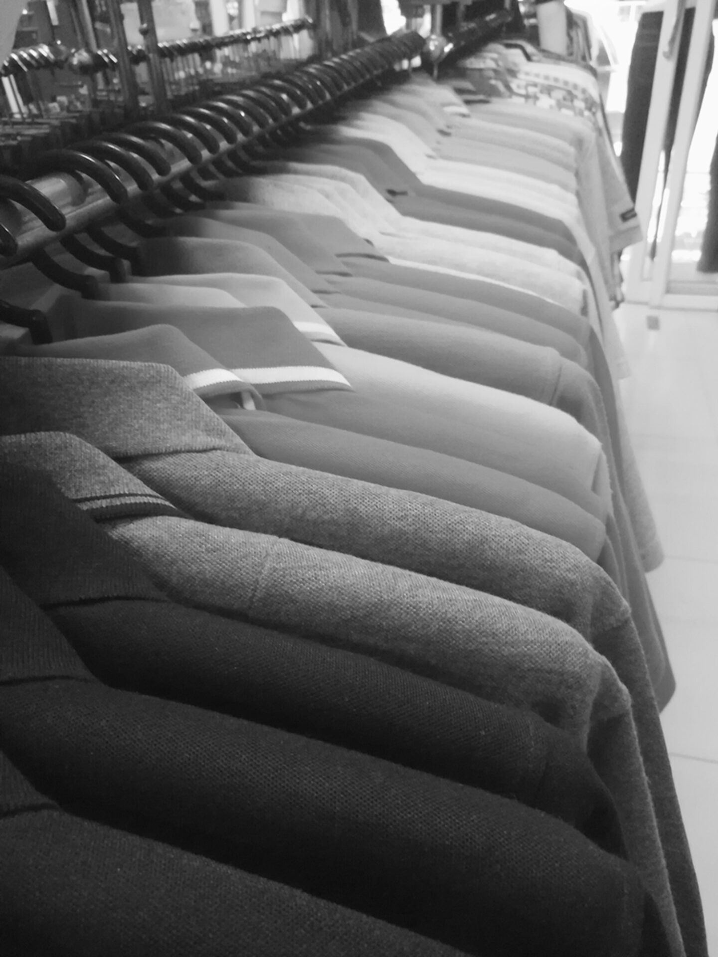 Black and white photo of finished knit polo shirts hanging on a rack in a garment factory, ready for shipment using PolyPM by Polygon Software, an ERP for garment manufacturing and a software for the garment industry