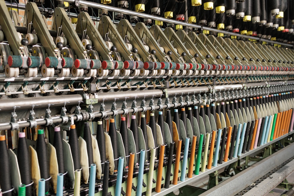 Industrial sewing machines in a modern textile factory showcasing apparel sourcing software for efficient apparel manufacturing operations.