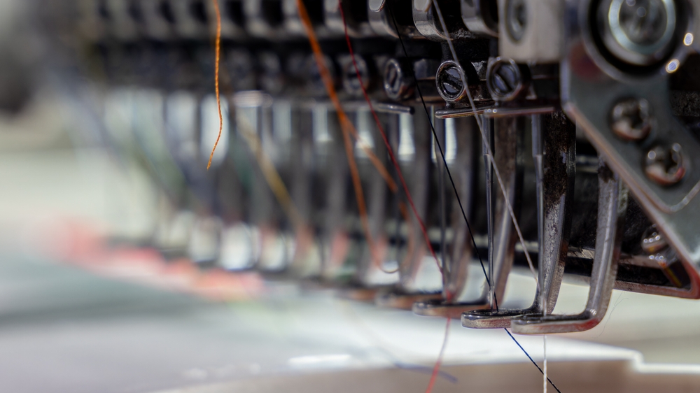 Automated sewing equipment producing garments in a clothing factory supported by apparel sourcing software for material sourcing and production planning.