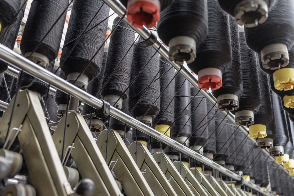 Industrial garment production line featuring advanced machinery managed with software for garment costing and margin analysis to optimize factory performance.