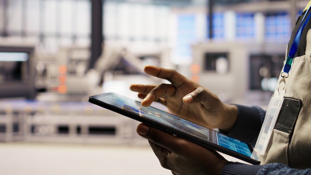 Production floor team reviewing apparel capacity planning software on a tablet during a shift