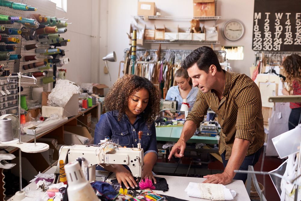 Small apparel manufacturing team reviewing production orders using apparel software for small business