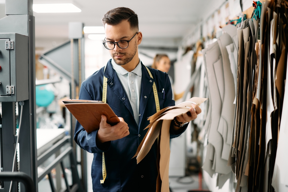 Cutting room operator reviewing a cut order planning software layout before spreading fabric