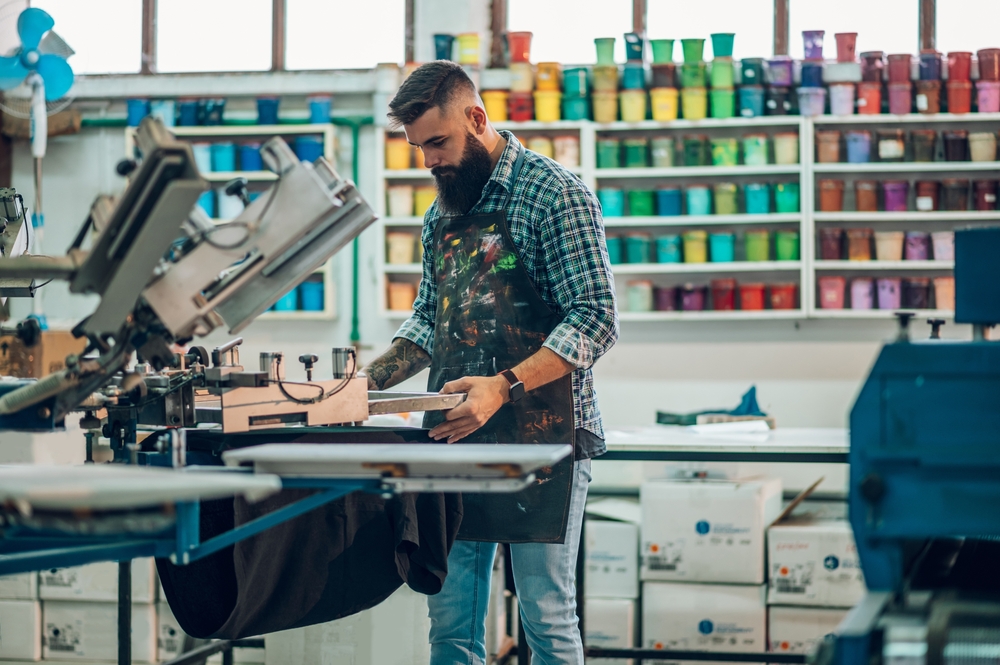 Screen printing station running a production order tracked by apparel decoration software on a factory floor
