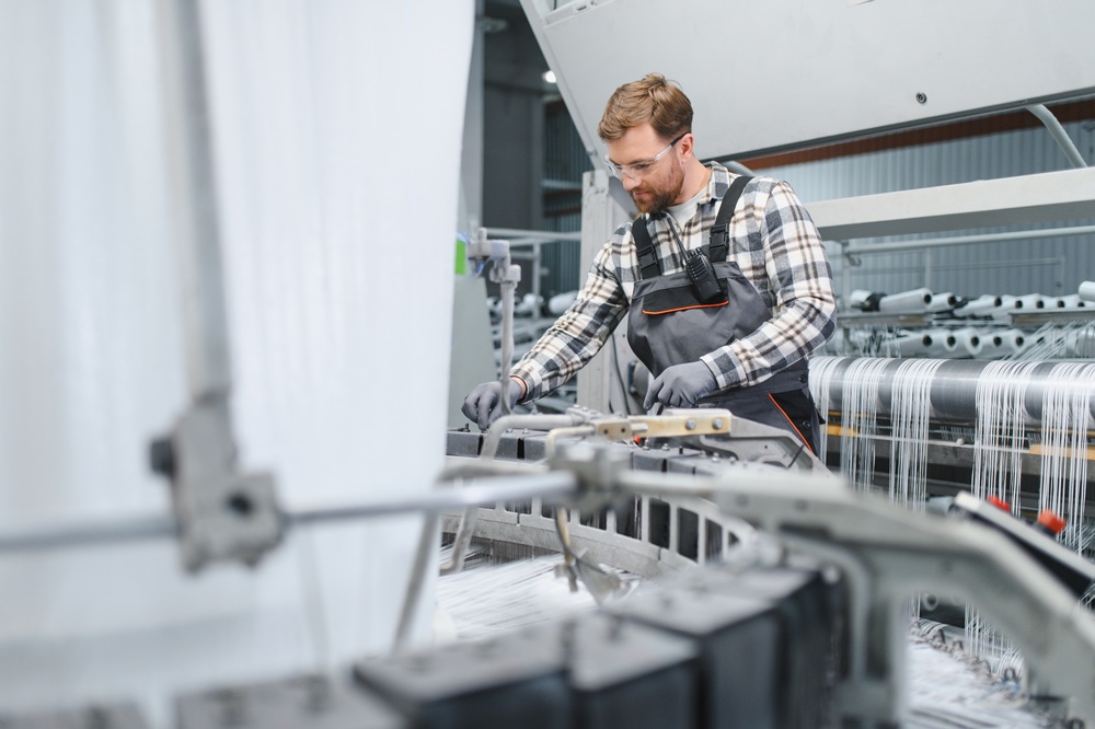 Worker measuring fabric thread as part of a fabric roll tracking software workflow