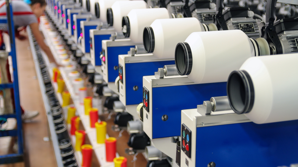 Cones of thread on a sewing machine organized with manufacturing inventory management software.
