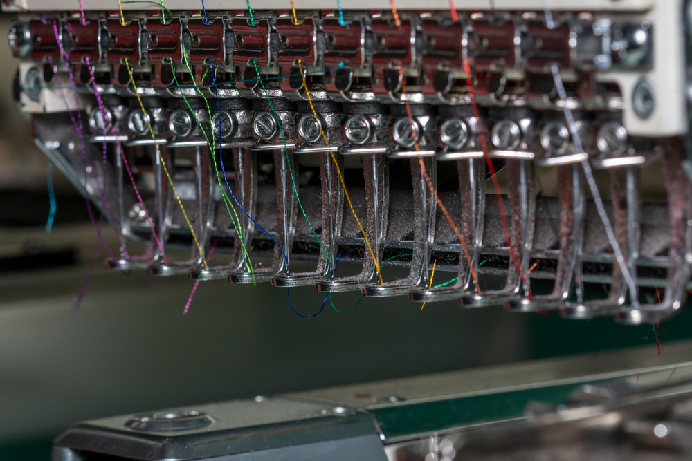 Industrial sewing machines in an apparel plant running manufacturing inventory management software.

