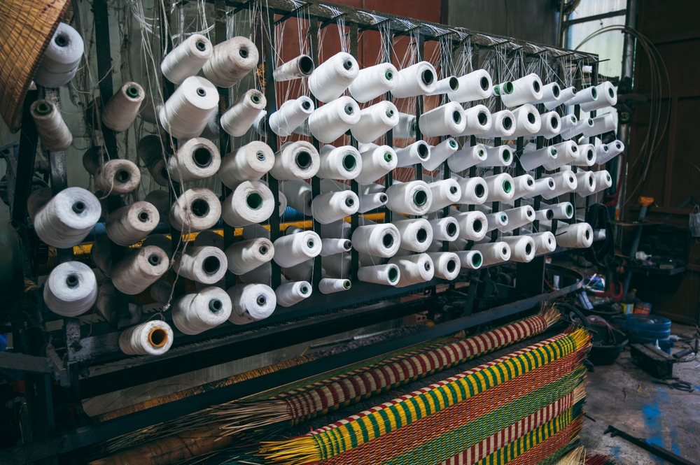Spools of industrial thread and trims in a factory running production management software for material planning